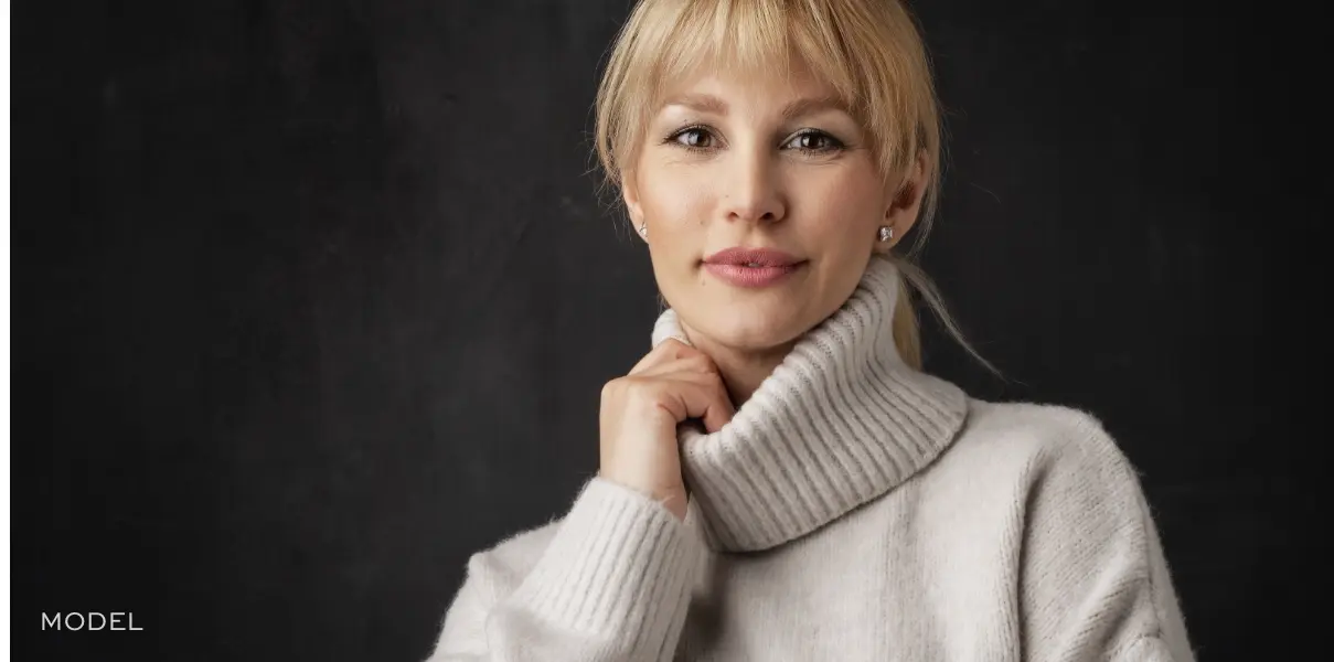 Women smiling at the camera and holding sweater